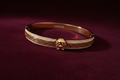 Gold Greek key bracelet on burgundy velvet – front view